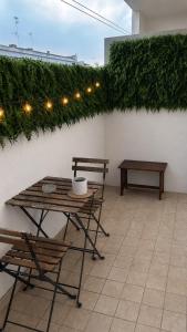 a patio with a table and chairs and a hedge at Modern apartment - Salento Guest House in Monteroni di Lecce
