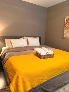 a bed with a yellow blanket and towels on it at White Rock Joy Inn in White Rock