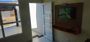 a living room with a tv and a door with a window at Casa 2 Quartos com Ar até 8 Pessoas Jd. Sabiás in Indaiatuba