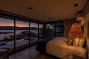 a bedroom with a bed with a view of the water at Morro Redondo - Bangalôs com vista do lago e da serra in CÃ¡ssia