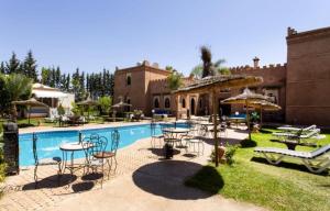 a pool with tables and chairs next to a house at Domaine Ghait in Had Abdallah Rhiat