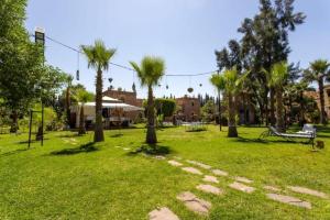 a park with palm trees and a bench in the grass at Domaine Ghait in Had Abdallah Rhiat