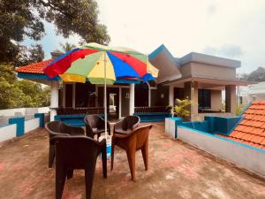a table with chairs and an umbrella in front of a house at Happy Home Varkala in Varkala