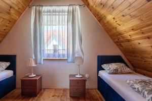 a attic bedroom with two beds and a window at Domki Oaza Spokoju in Nowęcin +26 photos