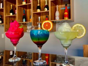 Drei Cocktails in Weingläsern stehen auf einer Bar. in der Unterkunft Gee Heights Private Boutique Guest House in Thabazimbi