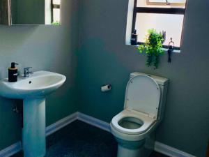 ein Badezimmer mit weißer Toilette und Waschbecken in der Unterkunft Gee Heights Private Boutique Guest House in Thabazimbi + 19 Fotos