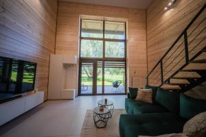 a living room with a green couch and a large window at Rusnės Vėjas in Rusnė