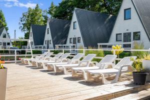 a row of white chairs sitting on a wooden deck at Soul Camp Nowęcin in Łeba