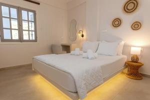 a white bedroom with a large white bed with white pillows at Sea View Kerame in Evdilos