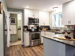 a kitchen with white cabinets and a stove top oven at Kulshan Cabin in Glacier +27 photos