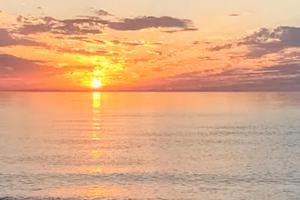 a sunset over a body of water at Steps to Beach & Lake Michigan! Family Retreat in Turner Shores