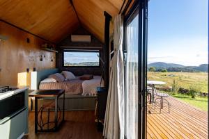 a bedroom in a tiny house with a large window at Tiny House - Rancho Queimado SC - 15 Min do centro in Rancho Queimado
