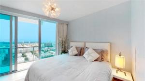 a bedroom with a white bed with a large window at Jade Beach Escape in Sunny Isles Beach +10 photos