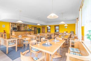 a restaurant with wooden tables and chairs and yellow walls at Rennerka Horská bouda in Strážné