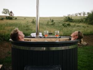 a man and a woman sitting in a barrel with wine glasses at Cserháti Házikó in Alsótold