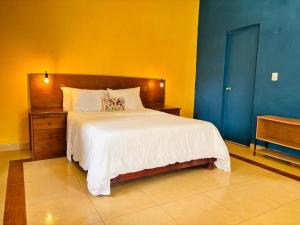 a bedroom with a bed and a blue and yellow wall at Loft Bugambilia en Casa Viva Merida in Techoh