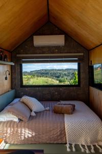 a bed in a small room with a window at Tiny House - Rancho Queimado SC - 15 Min do centro in Rancho Queimado