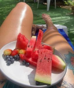 a person is holding a plate of watermelon and fruit at Pirita Beach House in Santa Ana