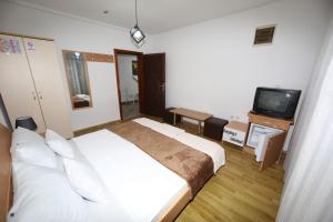 a bedroom with a white bed and a television at Villa Kaya in Ohrid