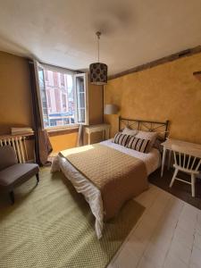 a bedroom with a bed and a chair and a window at Chambre d'hôtes Abbatiale in Bernay