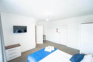 a white bedroom with a bed and a tv at The Bitterne Park Hotel in Southampton