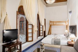 a bedroom with a bed and a tv and a window at Riad Noujoum Medina Fez in Fez