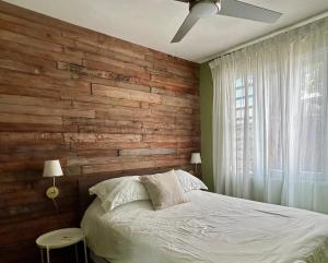 a bedroom with a wooden accent wall and a bed at Isla Verde By The Beach Guest House in San Juan