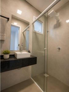 a bathroom with a sink and a glass shower at Yolanda Flats in Foz do Iguaçu