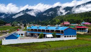 a large blue building with mountains in the background at Blue Bird Resort Utror Swat in Utrot