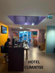 a man sitting at a desk in a hotel clinic at Unisotel Lyon Bron Eurexpo in Bron