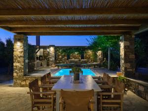 a patio with a table and chairs and a pool at SeaSalt Dream Villa,Santa Maria 5 min from Naousa in Santa Marina