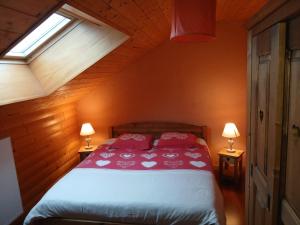 a bedroom with a bed with red sheets and a window at gite des granges bailly in Les Fourgs