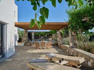 a patio with tables and chairs under a wooden pergola at SeaSalt Dream Villa,Santa Maria 5 min from Naousa in Santa Marina