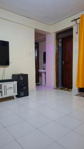 a living room with a television and a white tile floor at Boston apartments in Kakamega