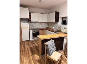 a kitchen with white cabinets and a table and a chair at O cantinho da Esther in Bustos