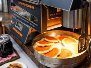 a fryer with pancakes in a pan on a counter at Anshin oyado Tokyo Woman Shinjuku Ogikubo in Tokyo
