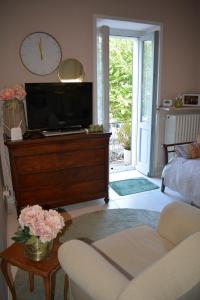 a living room with a tv on a dresser with a clock at Camelia in Arona