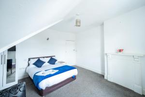 a white bedroom with a bed with blue pillows at The Bitterne Park Hotel in Southampton
