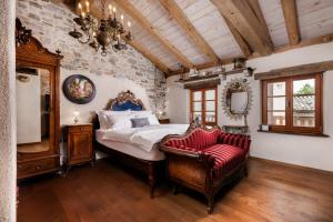 a bedroom with a bed and a chair at Krasna Hiška - Authentic Heritage Home in Sežana