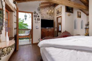 a bedroom with a bed and a television and a balcony at Krasna Hiška - Authentic Heritage Home in Sežana
