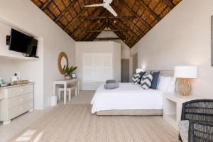 a white bedroom with a bed and a television at CANAL GUEST HOUSE - Waterfront Boutique B&B in St Francis Bay