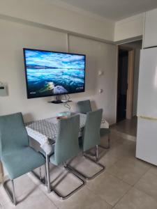 a dining room with a table and chairs and a flat screen tv at Blue Serenity in Nea Vrasna