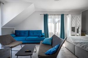 a living room with a blue couch and a bed at Pokoje Oaza Spokoju in Nowęcin +42 photos