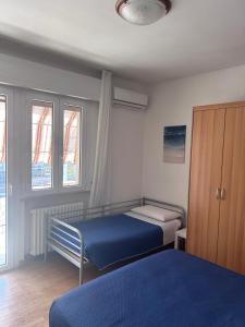 a bedroom with two beds and a cabinet and windows at Appartamento Ares in Misano Adriatico