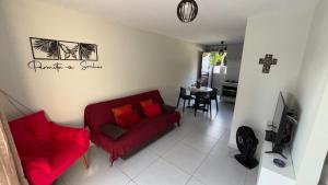 a living room with a red couch and a table at Flat Forte Orange - Ilha de Itamaracá in Itamaracá