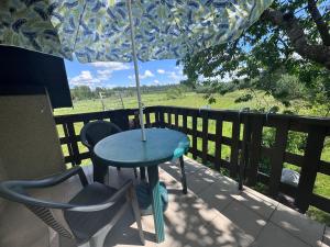 a table and chairs on a porch with an umbrella at Domek u Moni Kaszuby in Sulęczyno