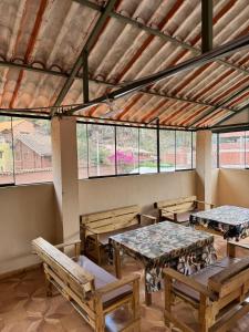 a large room with tables and benches and windows at Hospedaje Shalom in Pisac