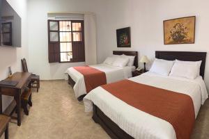 a hotel room with two beds and a desk at Hotel La Plazuela in Popayan