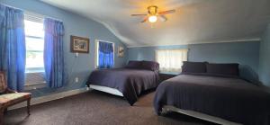 a blue bedroom with two beds and a ceiling fan at Niagara Historic Inn in Lockport