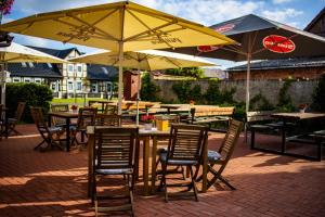 eine Gruppe von Tischen und Stühlen mit Sonnenschirmen in der Unterkunft Restaurant und Pension Zur Wildgans in Arendsee